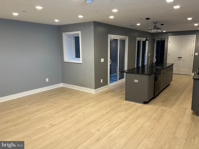 kitchen with sink, decorative light fixtures, dishwasher, light hardwood / wood-style flooring, and a center island with sink