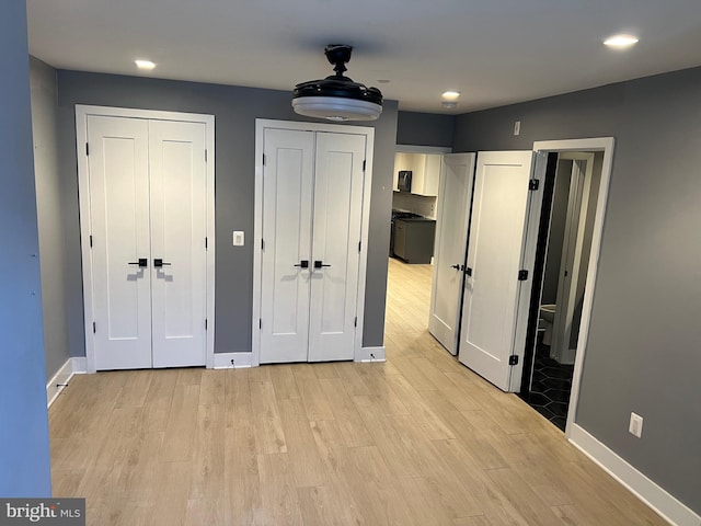 unfurnished bedroom with two closets, ceiling fan, and light hardwood / wood-style floors