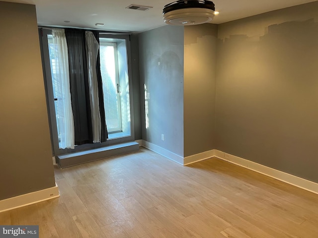 empty room featuring light wood finished floors, visible vents, and baseboards