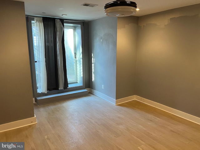 empty room with light wood finished floors, baseboards, and visible vents