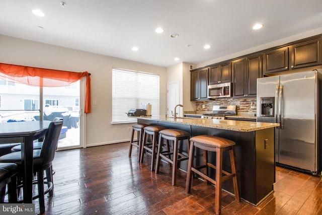 kitchen featuring dark brown cabinetry, plenty of natural light, an island with sink, and appliances with stainless steel finishes