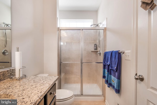 bathroom featuring vanity, a shower with shower door, and toilet