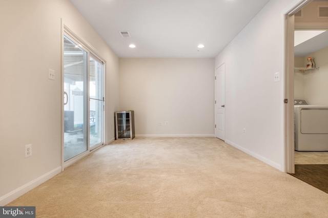 spare room featuring beverage cooler, light colored carpet, and washer / dryer