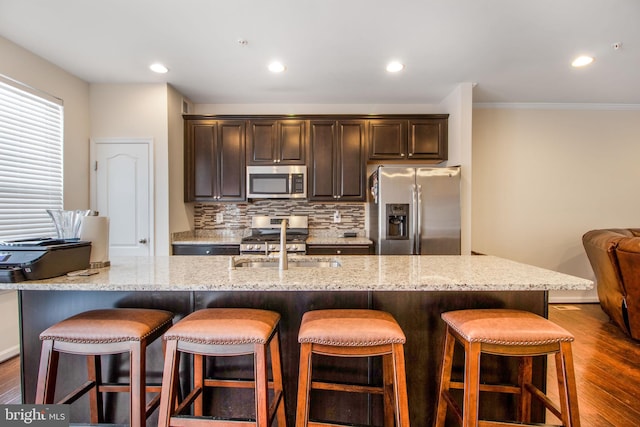 kitchen with a large island with sink, sink, a breakfast bar, and appliances with stainless steel finishes