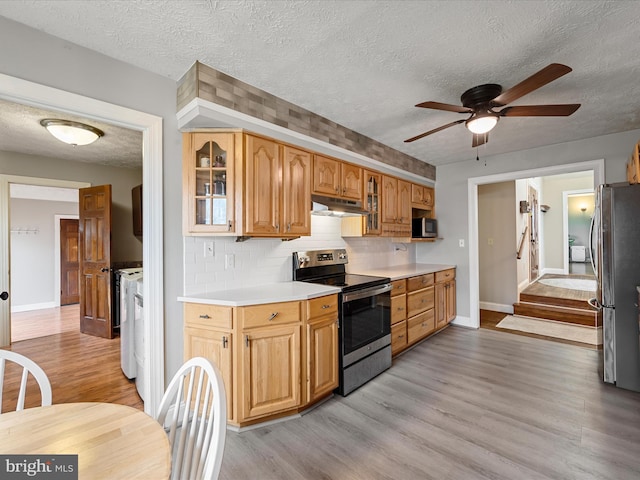 kitchen featuring ceiling fan, a textured ceiling, appliances with stainless steel finishes, and light hardwood / wood-style flooring