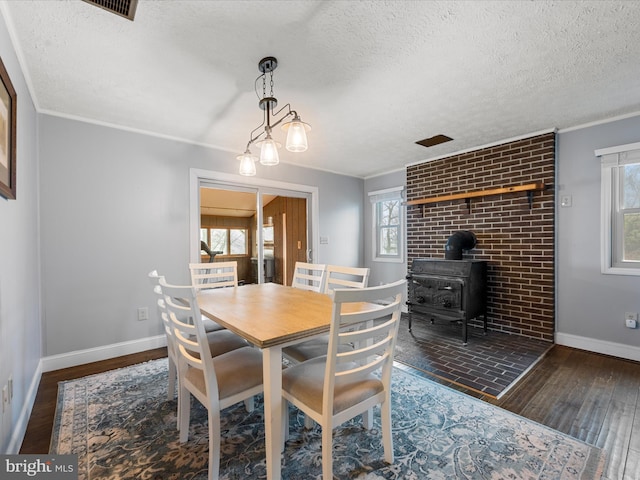 dining area with dark hardwood / wood-style floors, plenty of natural light, a wood stove, and a textured ceiling