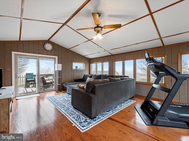 living room featuring hardwood / wood-style floors, ceiling fan, wood walls, and vaulted ceiling