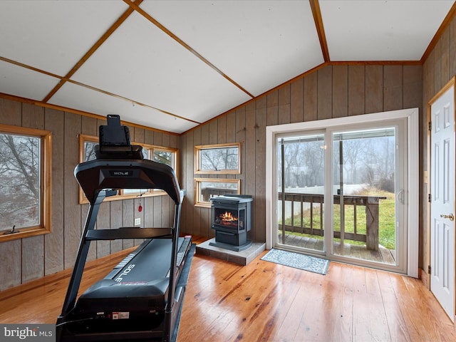 workout room featuring vaulted ceiling, hardwood / wood-style flooring, a wood stove, and wooden walls