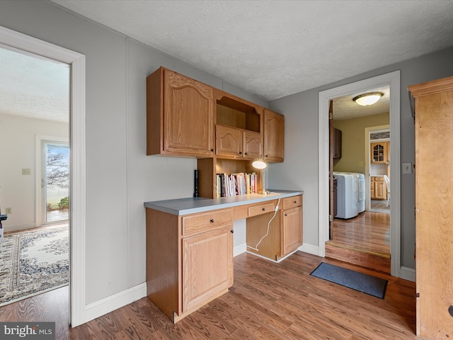 kitchen with a textured ceiling, built in desk, and light hardwood / wood-style floors