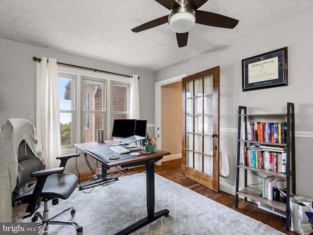 home office featuring ceiling fan, french doors, dark wood-type flooring, and a textured ceiling