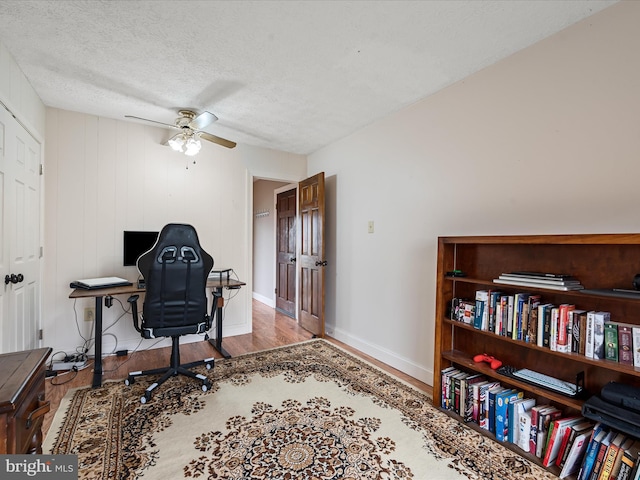 office area with hardwood / wood-style floors, ceiling fan, and a textured ceiling