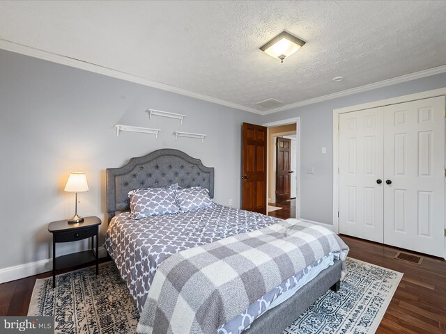 bedroom with a textured ceiling, dark hardwood / wood-style floors, crown molding, and a closet