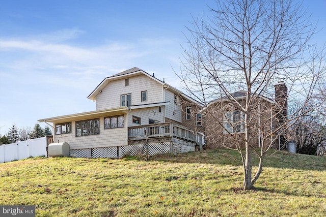 rear view of property featuring a wooden deck and a lawn