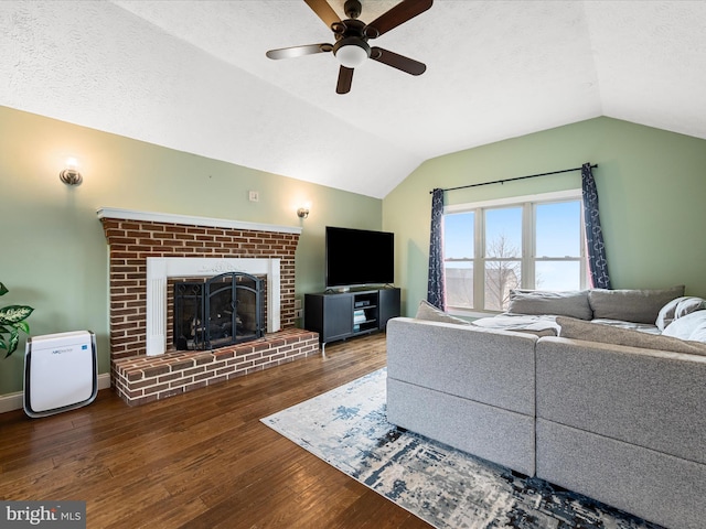 living room featuring a brick fireplace, dark hardwood / wood-style floors, ceiling fan, and vaulted ceiling