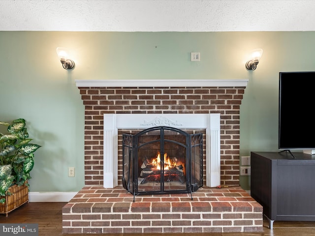 details with a textured ceiling, hardwood / wood-style flooring, and a brick fireplace