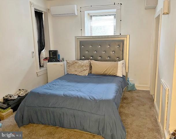 bedroom featuring an AC wall unit and light carpet