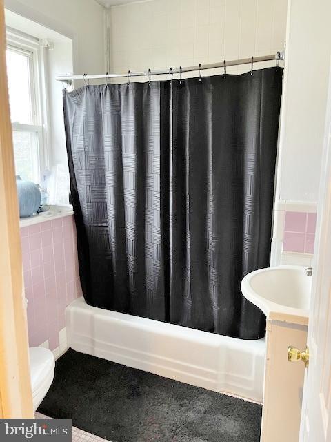 full bathroom with shower / bathtub combination with curtain, vanity, tile walls, and toilet