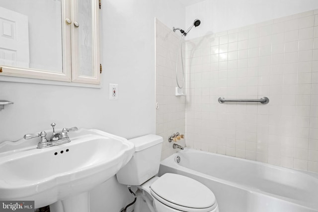 full bathroom featuring sink, tiled shower / bath, and toilet