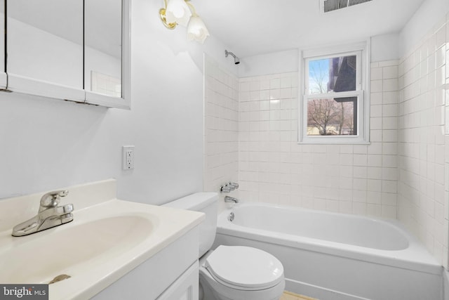 full bathroom featuring tiled shower / bath, vanity, and toilet