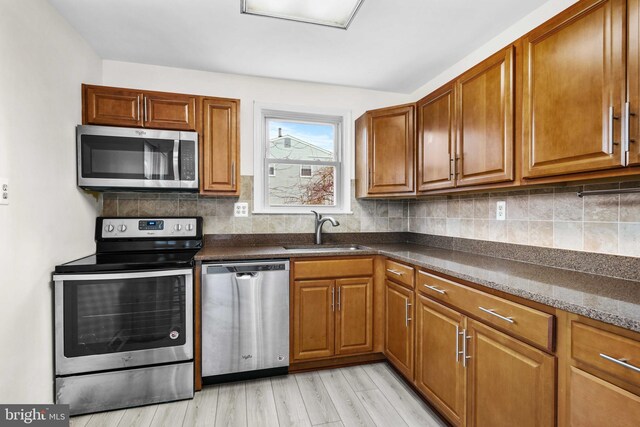 kitchen featuring decorative backsplash, sink, stainless steel appliances, and light hardwood / wood-style floors