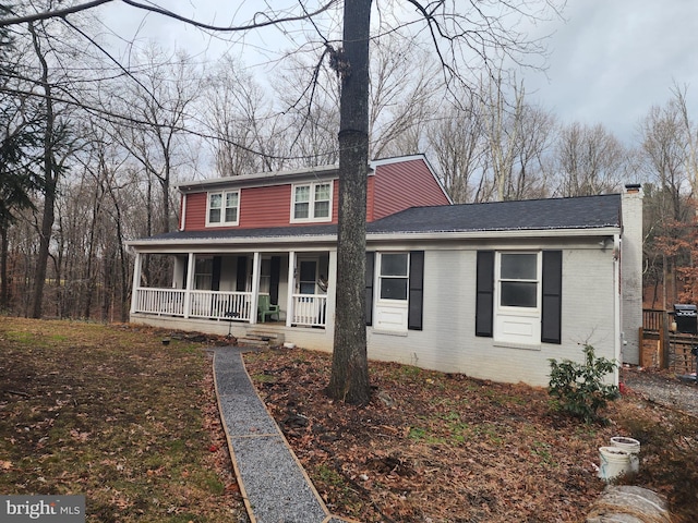 traditional-style house with brick siding, covered porch, and a chimney