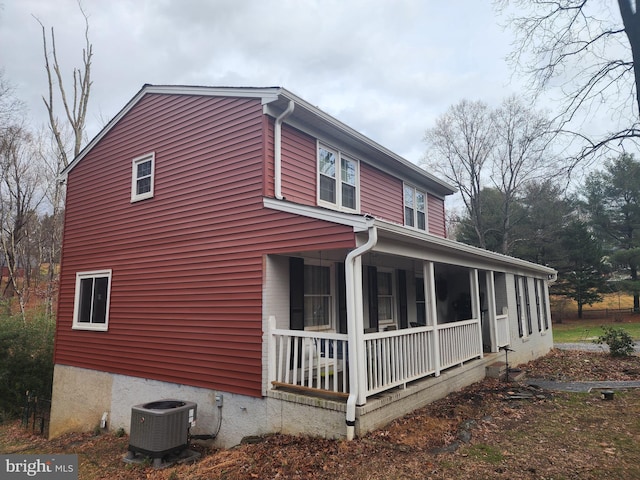 view of side of home with covered porch and central AC