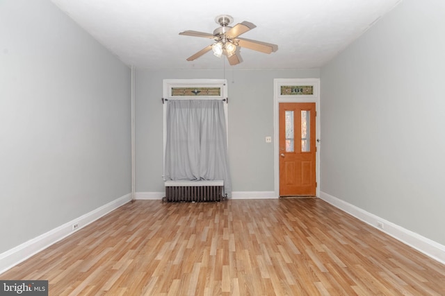 unfurnished room with radiator, ceiling fan, and light wood-type flooring