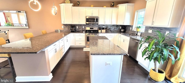 kitchen with sink, a center island, a kitchen breakfast bar, decorative light fixtures, and appliances with stainless steel finishes