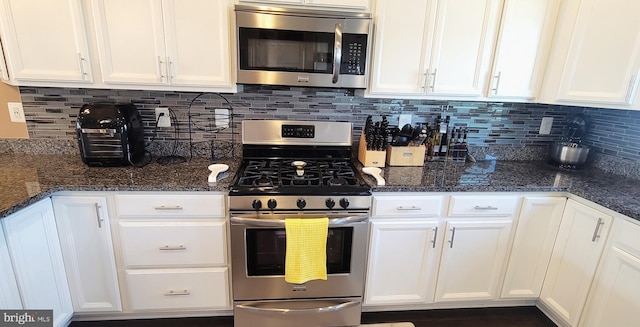 kitchen featuring appliances with stainless steel finishes, tasteful backsplash, white cabinetry, and dark stone counters