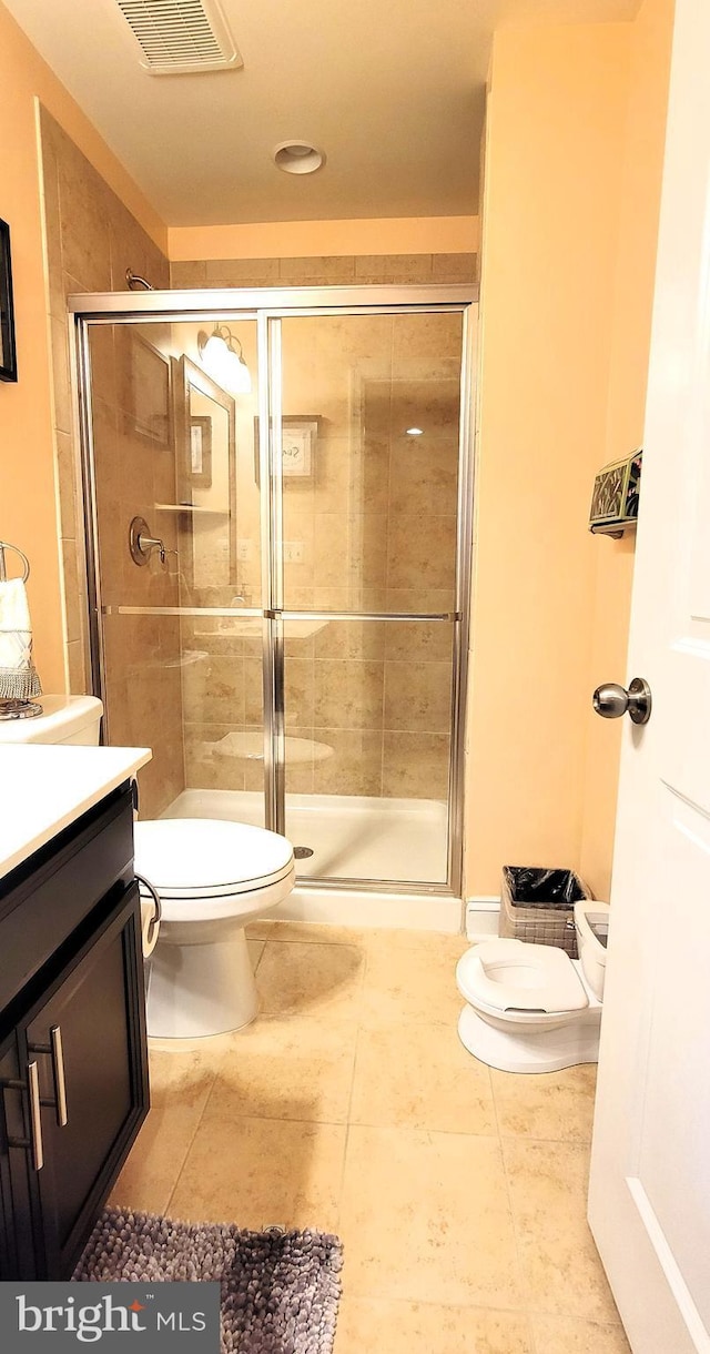 bathroom featuring tile patterned flooring, vanity, toilet, and walk in shower