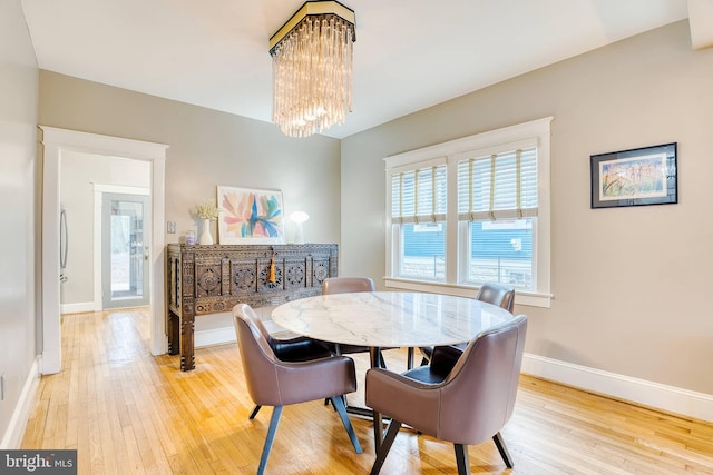 dining space with wood-type flooring and an inviting chandelier