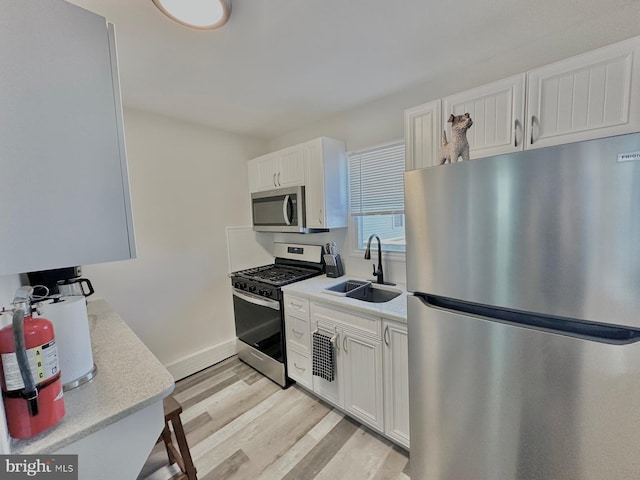 kitchen featuring sink, white cabinetry, stainless steel appliances, and light wood-type flooring