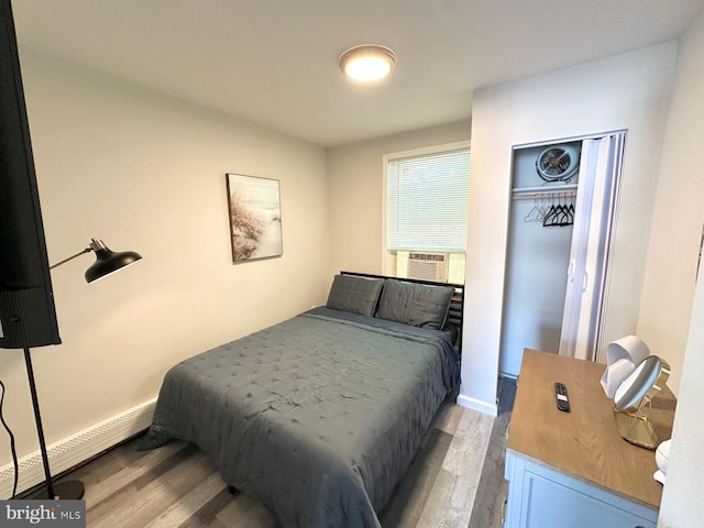 bedroom featuring cooling unit, a baseboard heating unit, a closet, and light hardwood / wood-style flooring