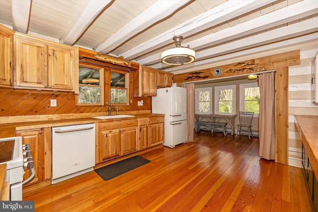 kitchen featuring beam ceiling, sink, dark wood-type flooring, wood walls, and white appliances