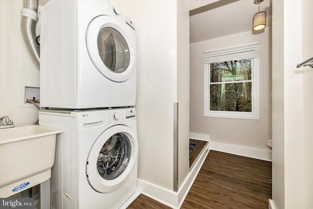 washroom with dark hardwood / wood-style floors, stacked washer and clothes dryer, and sink