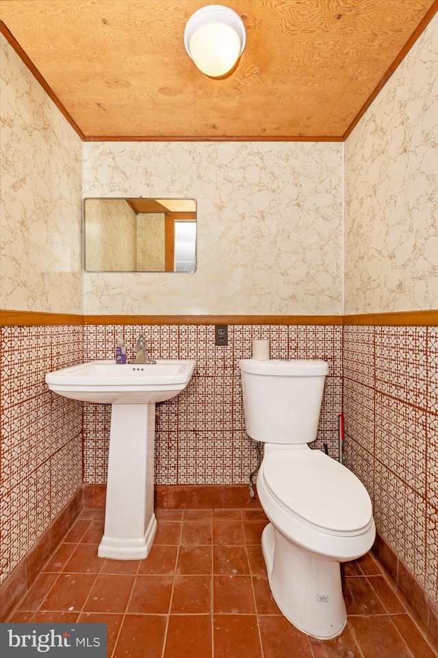 bathroom with tile patterned flooring, toilet, tile walls, and crown molding