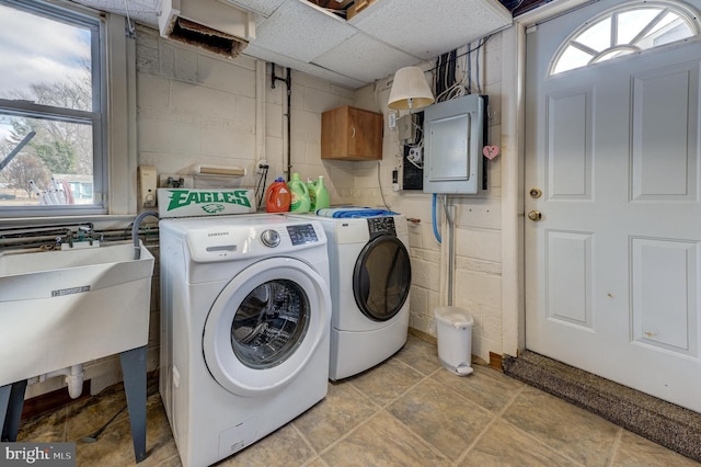 laundry area with electric panel, separate washer and dryer, sink, and cabinets