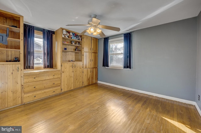 empty room featuring ceiling fan, wood-type flooring, and wooden walls