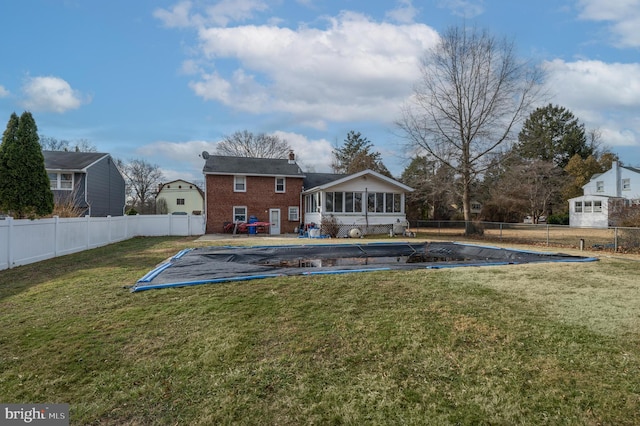 rear view of property featuring a sunroom, a yard, and a covered pool