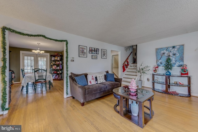 living room featuring a chandelier, a textured ceiling, and light hardwood / wood-style floors