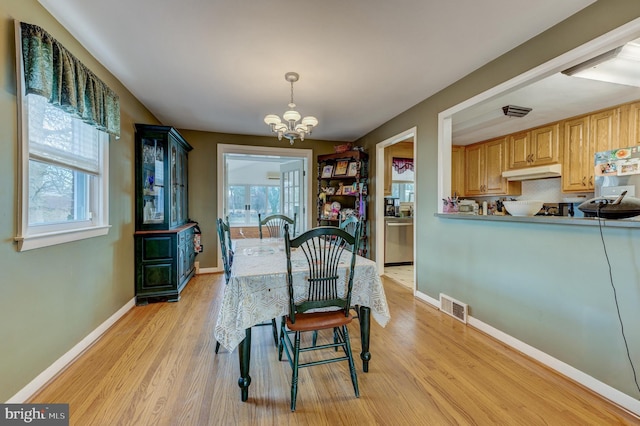 dining area featuring light hardwood / wood-style floors and a notable chandelier