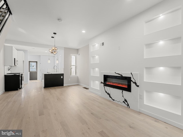 unfurnished living room with heating unit, sink, and light hardwood / wood-style floors