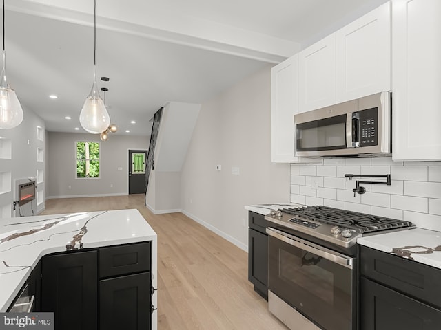 kitchen with white cabinetry, light hardwood / wood-style flooring, hanging light fixtures, and appliances with stainless steel finishes