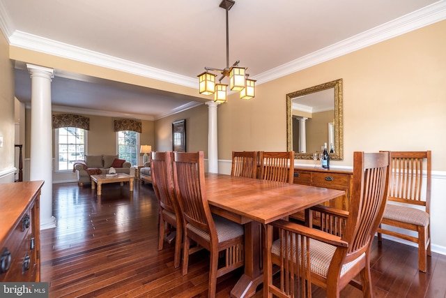 dining space featuring ornate columns, crown molding, dark hardwood / wood-style flooring, and an inviting chandelier