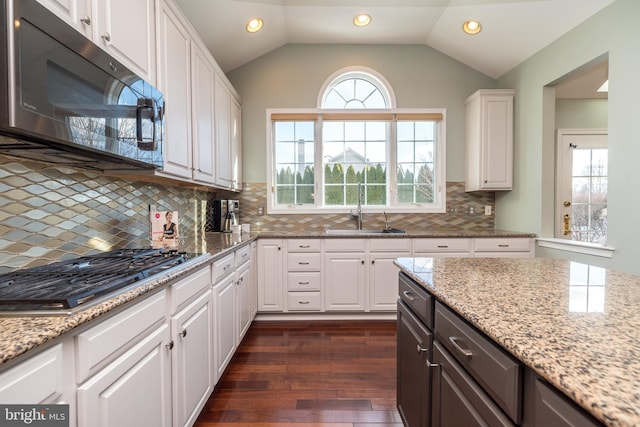 kitchen featuring sink, vaulted ceiling, decorative backsplash, white cabinetry, and stainless steel appliances