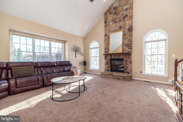 carpeted living room featuring a stone fireplace and high vaulted ceiling