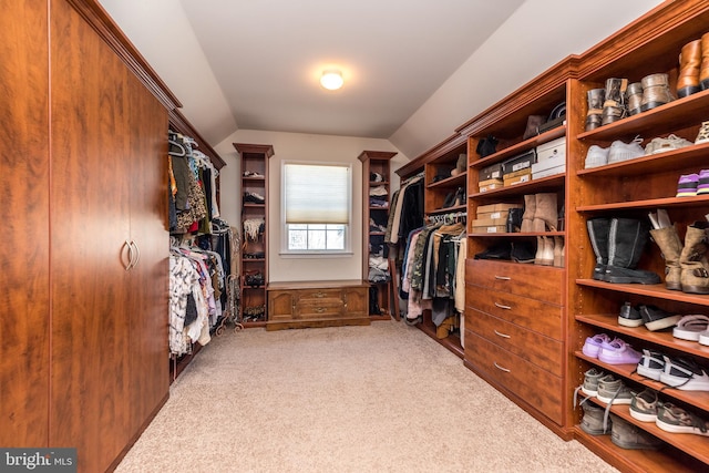 walk in closet featuring light colored carpet and lofted ceiling