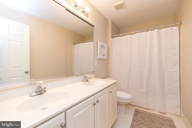 bathroom with toilet, vanity, and tile patterned floors