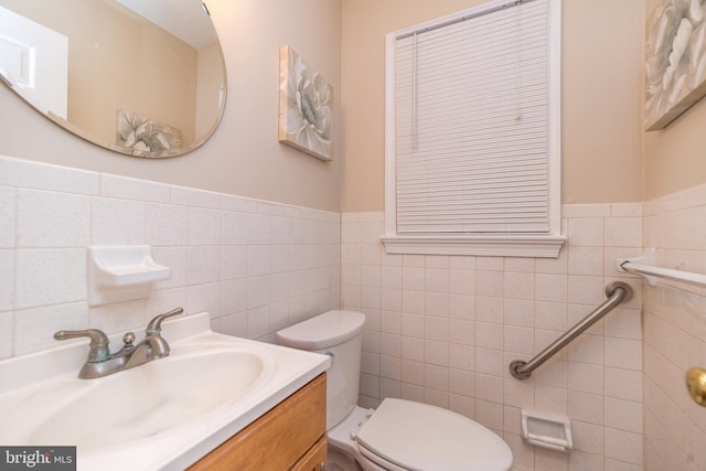 bathroom with vanity, toilet, and tile walls