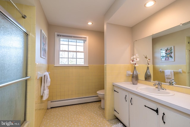 bathroom with baseboard heating, tile patterned flooring, toilet, vanity, and tile walls